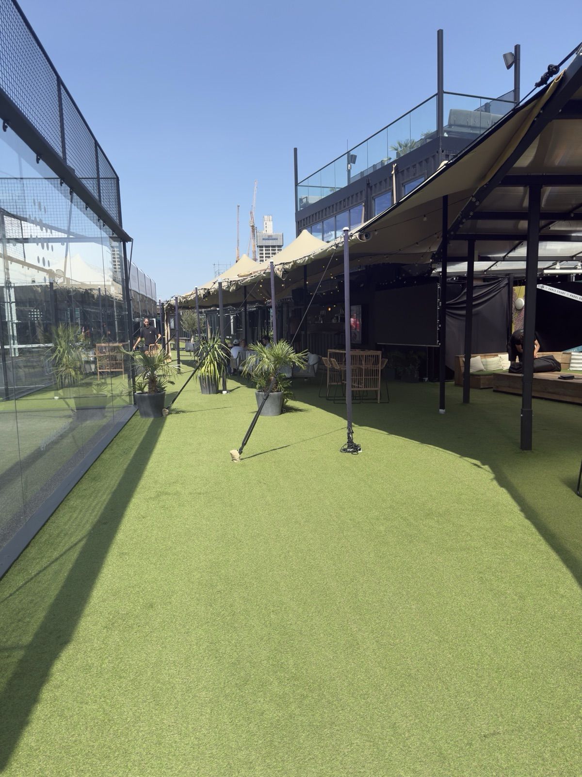 The fairy-lit canopy and exotic plants running alongside the bar on the turf at Padel Social Club Earls Court.