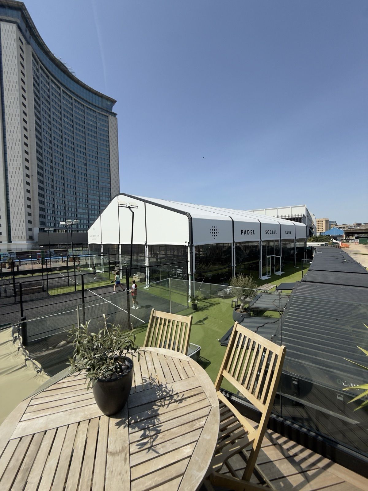 The rooftop terrace at Padel Social Club Earls Court, overlooking the marquee-covered courts and the London skyline.