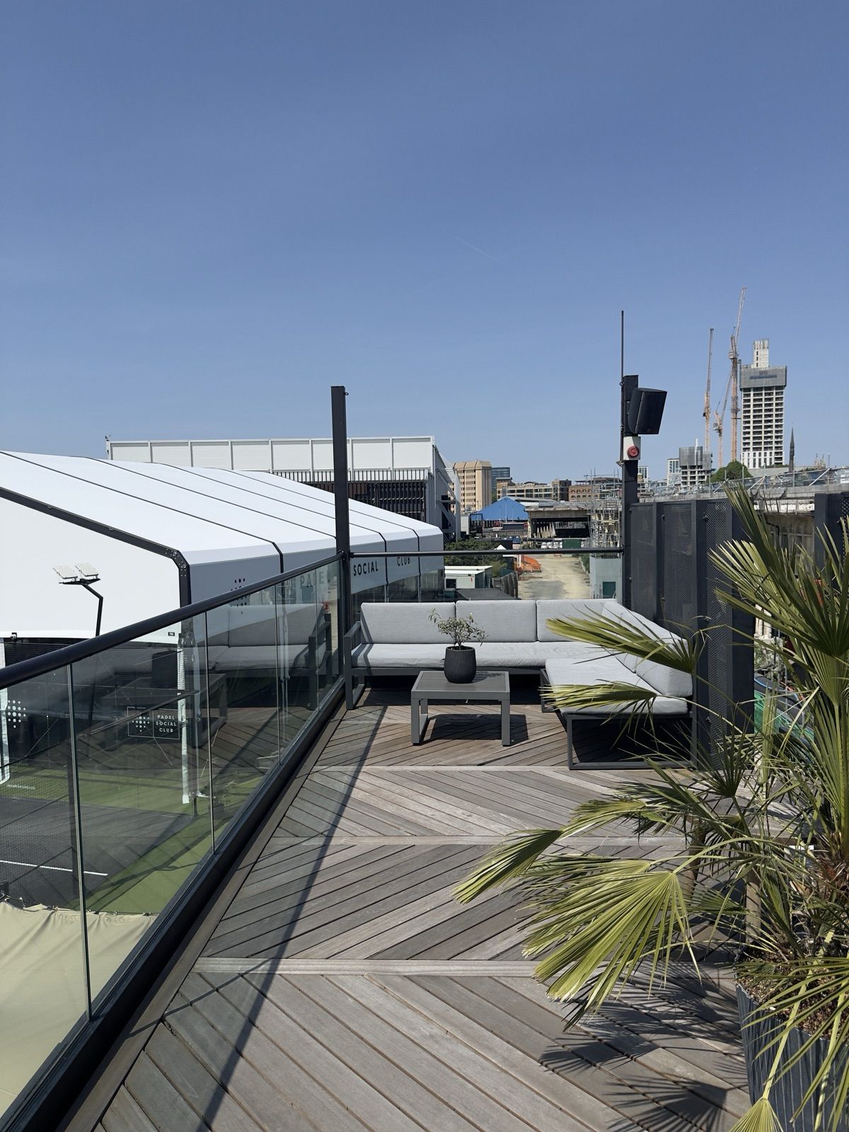 The rooftop terrace lounge at Padel Social Club Earls Court overlooking the courts and the London skyline.