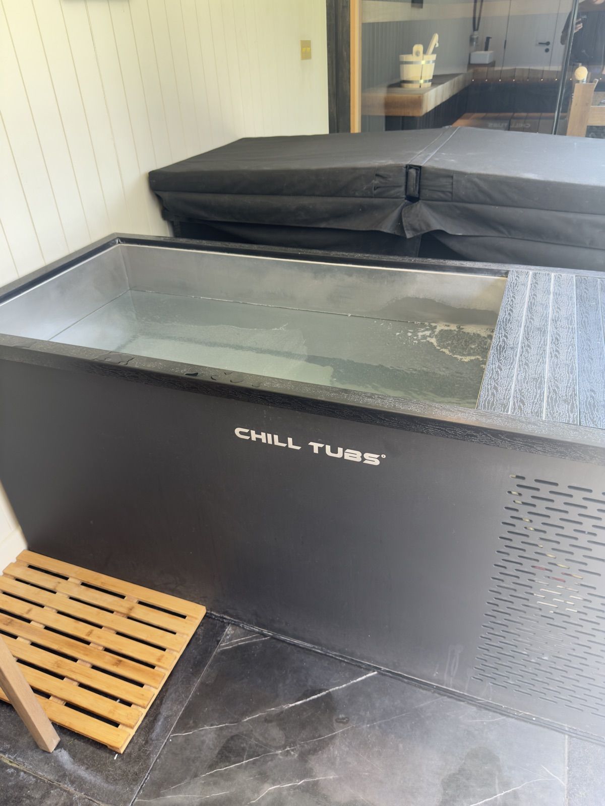 The wellness room at Padel Social Club Earls Court: a Chill Tubs ice bath with the sauna beyond.