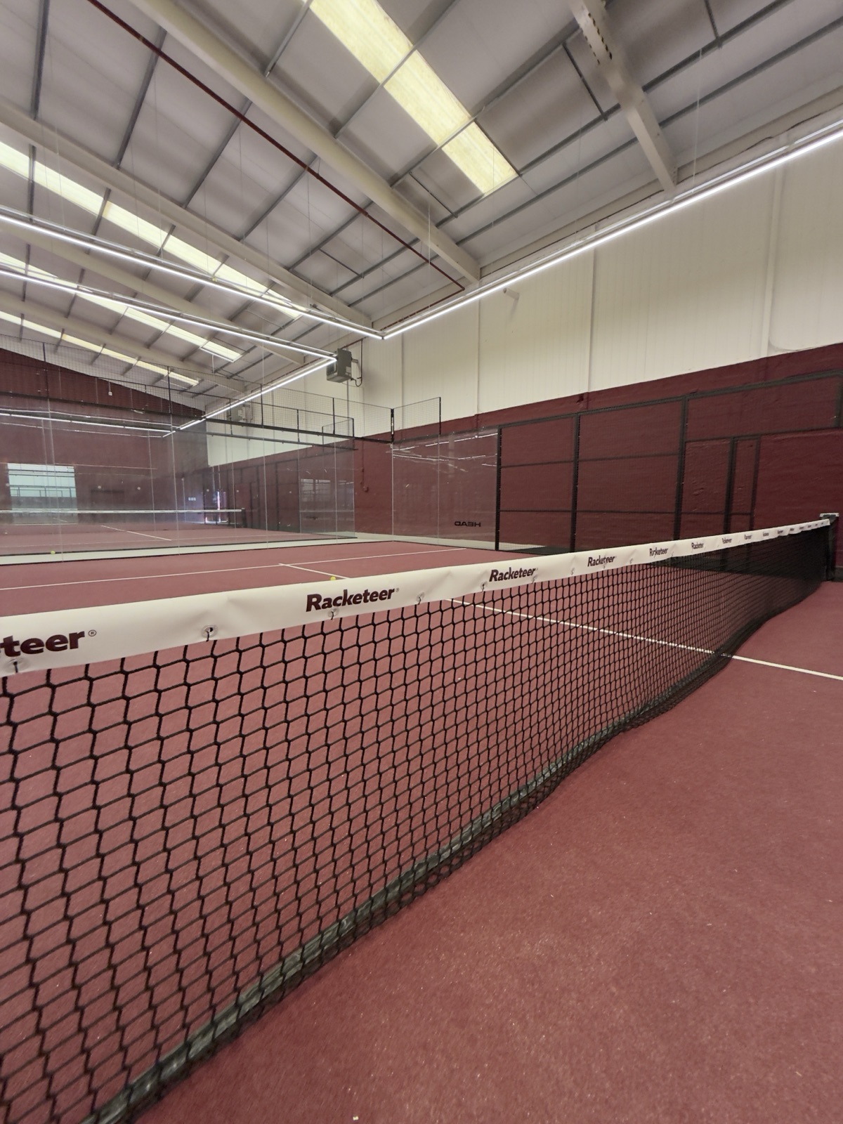 The red-turf padel courts inside the Racketeer warehouse.