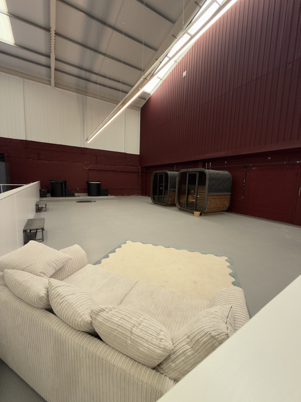The makeshift wellness area at Racketeer: a sofa and open floor, with sauna pods beyond.